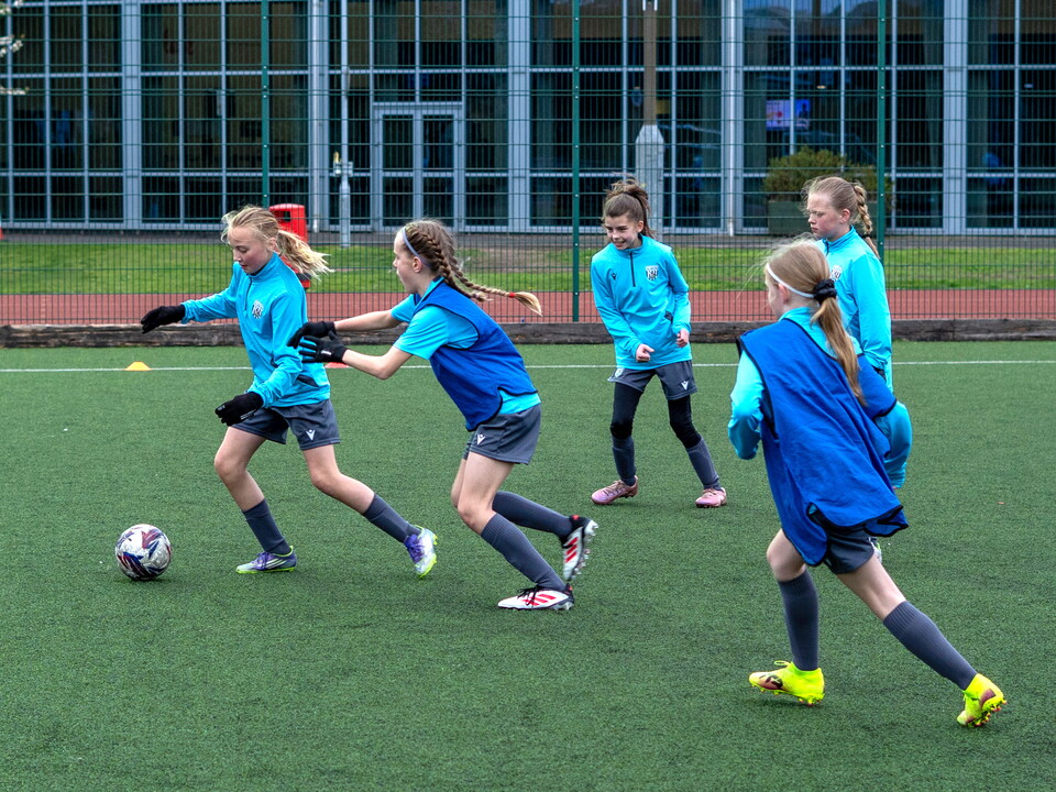 Players dribbling the ball with players in bibs chasing.