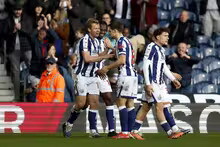 Three players in blue and white striped shirts celebrate a goal.