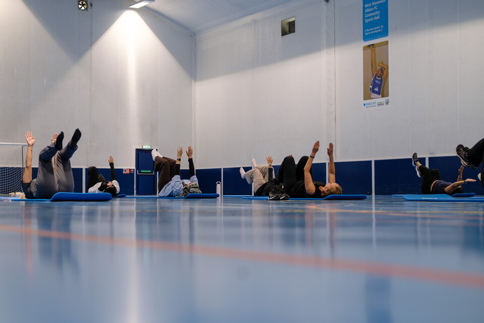 Wide image of women laying down with feet raised in a pilates position 