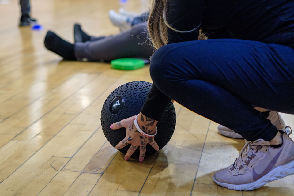 Participant with her hands around a medicine ball.