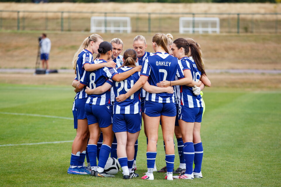 Albion Women in a team huddle in the home kit before a pre-season friendly against Real Bedford 