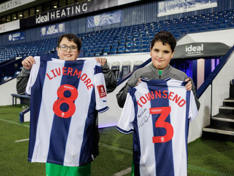 James & Richard holding shirts signed by Livermore & Townsend 