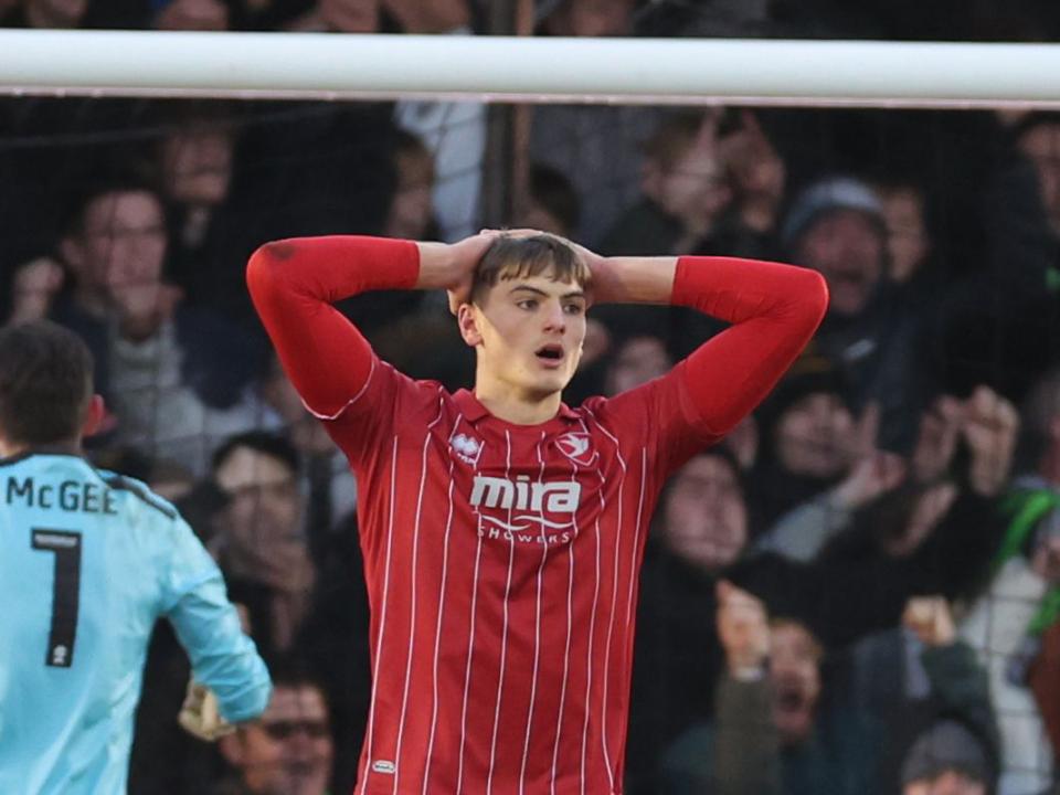 Caleb Taylor puts his hands on his head wearing a Cheltenham shirt