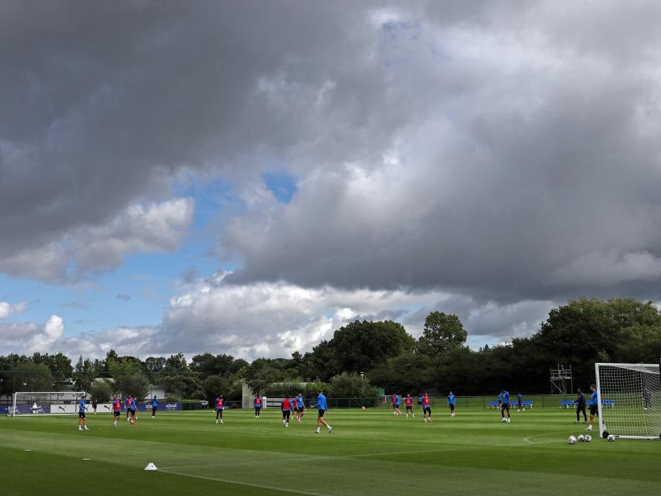 A wide angle of the training pitch with several players in the background