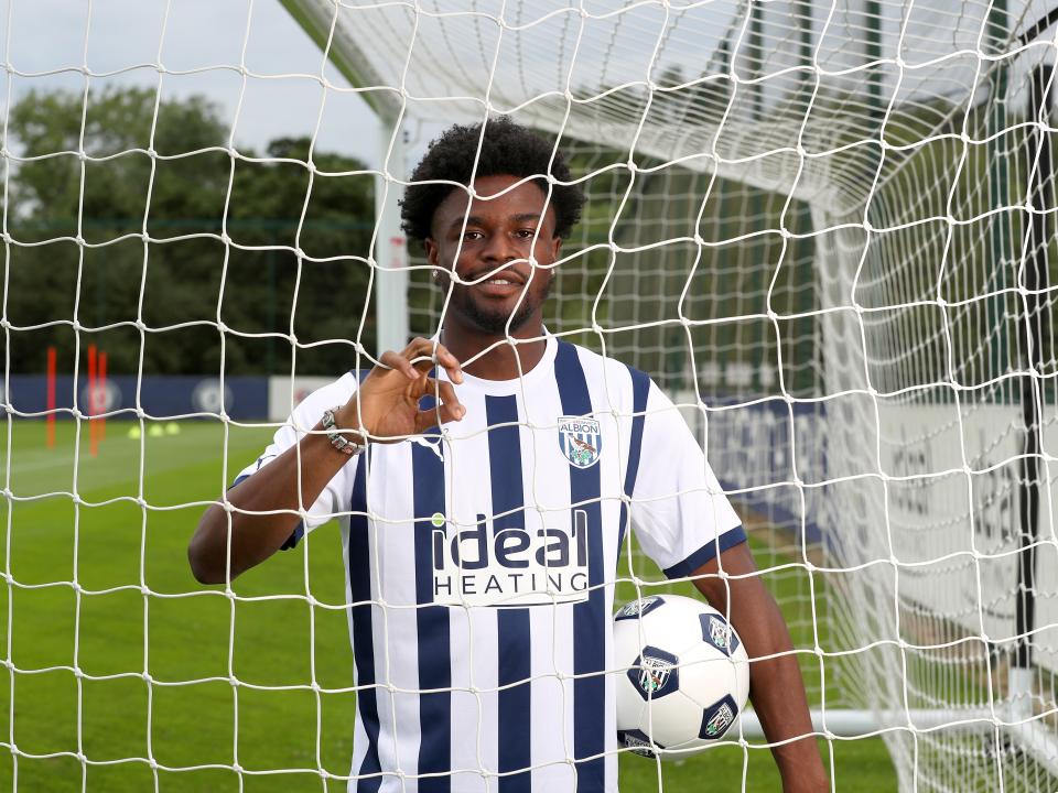 Josh Maja in an Albion shirt looking through a goal net