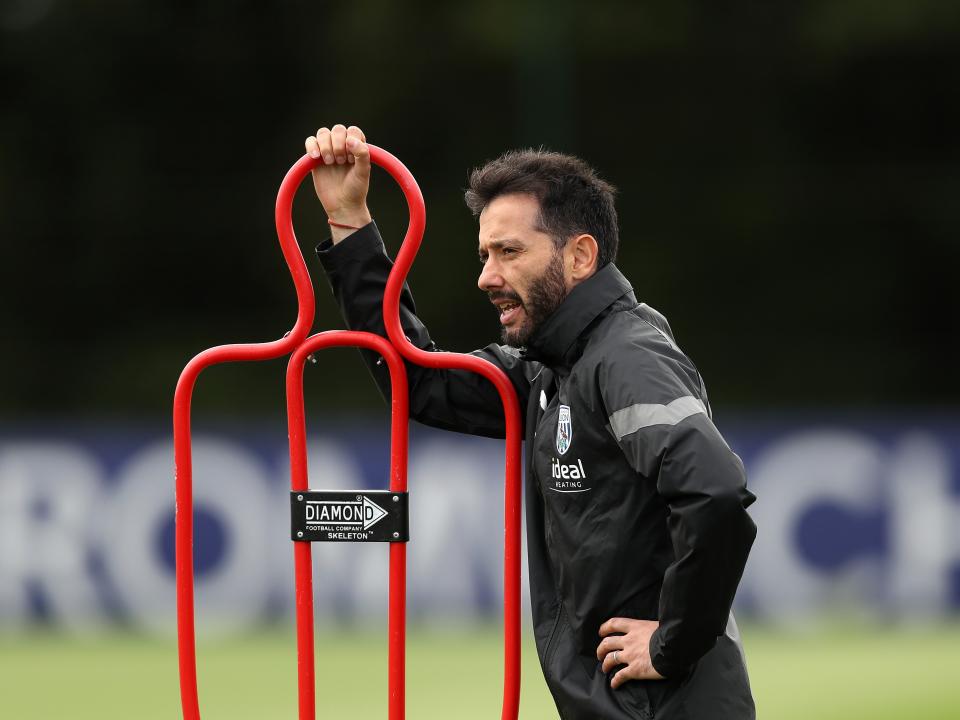 Carlos Corberán leaning on a training mannequin
