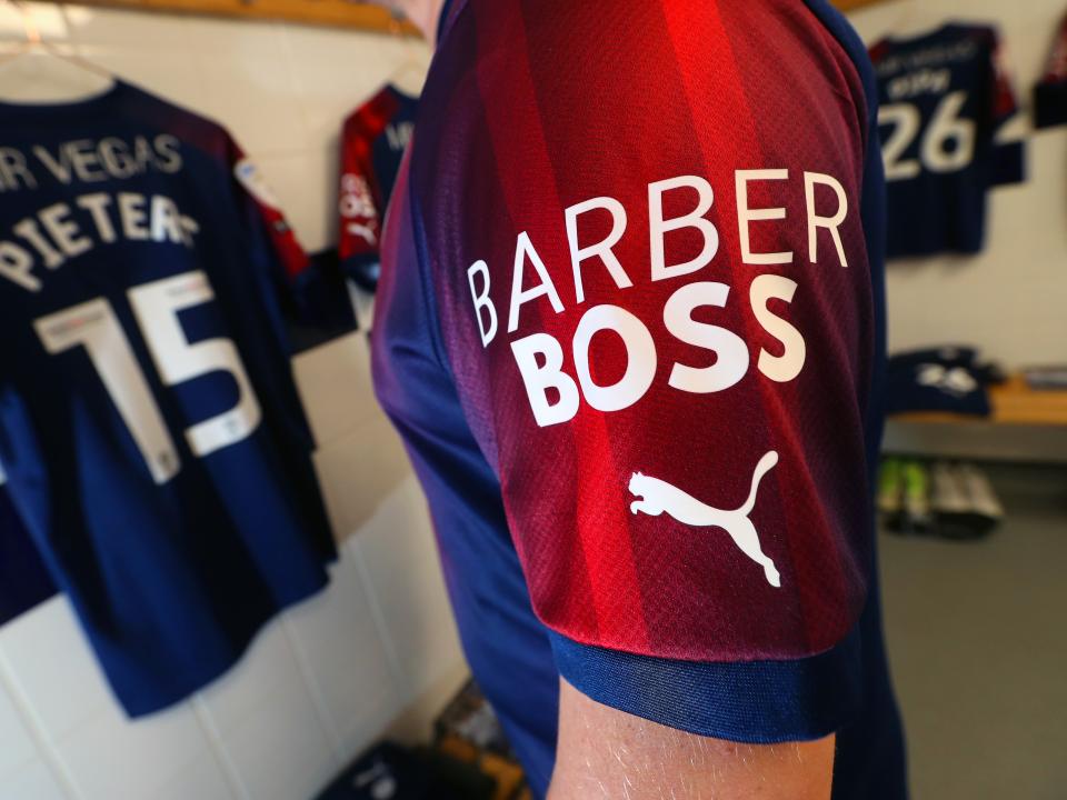 The Barber Boss logo on the sleeve of an Albion shirt.