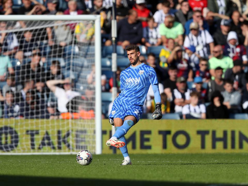Alex Palmer passing the ball wearing the blue goalkeeper kit