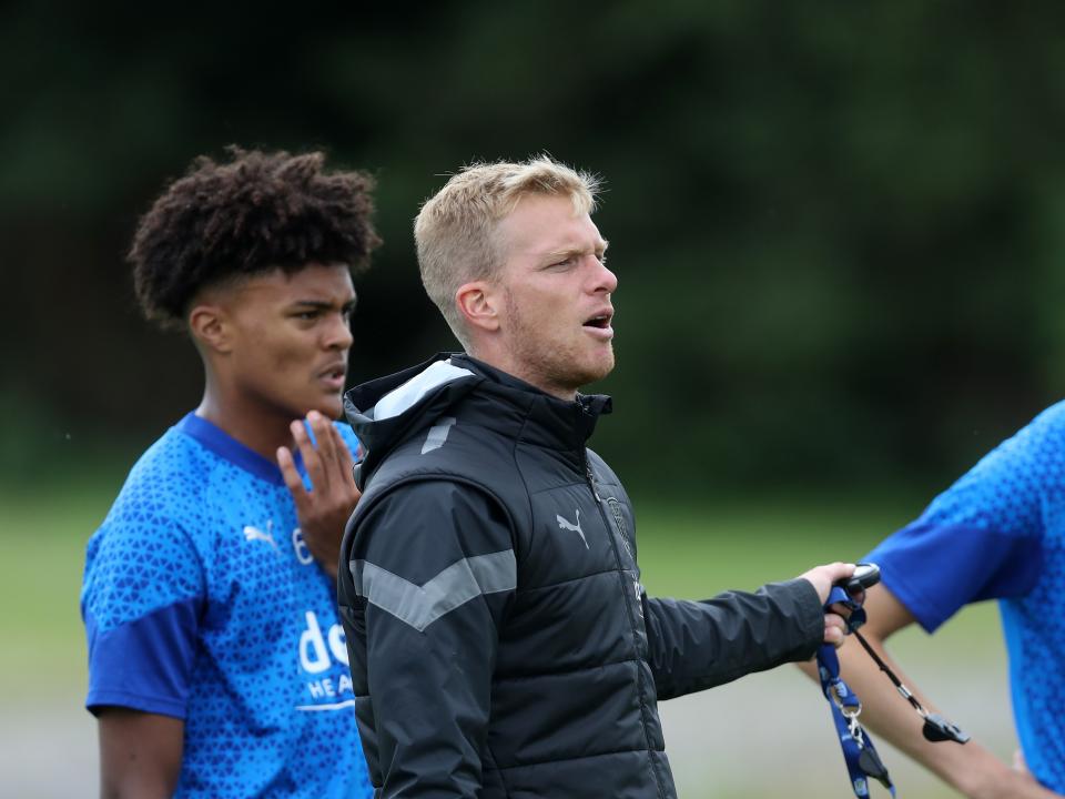 A photo of Albion Under 18s boss Leigh Downing, in black training gear, overseeing training on the back pitches of the club's Walsall training ground