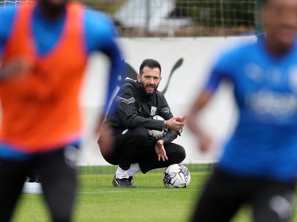 Carlos Corberán crouched down watching over training 