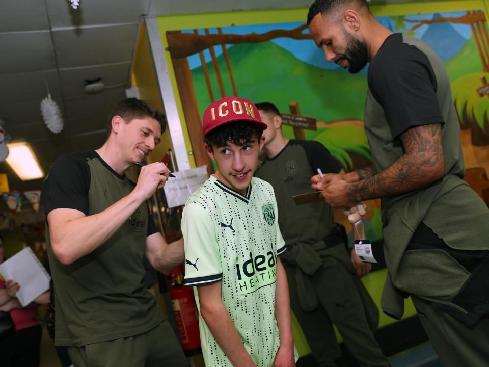 Adam Reach signs the back of a young supporter's shirt at Sandwell General Hospital