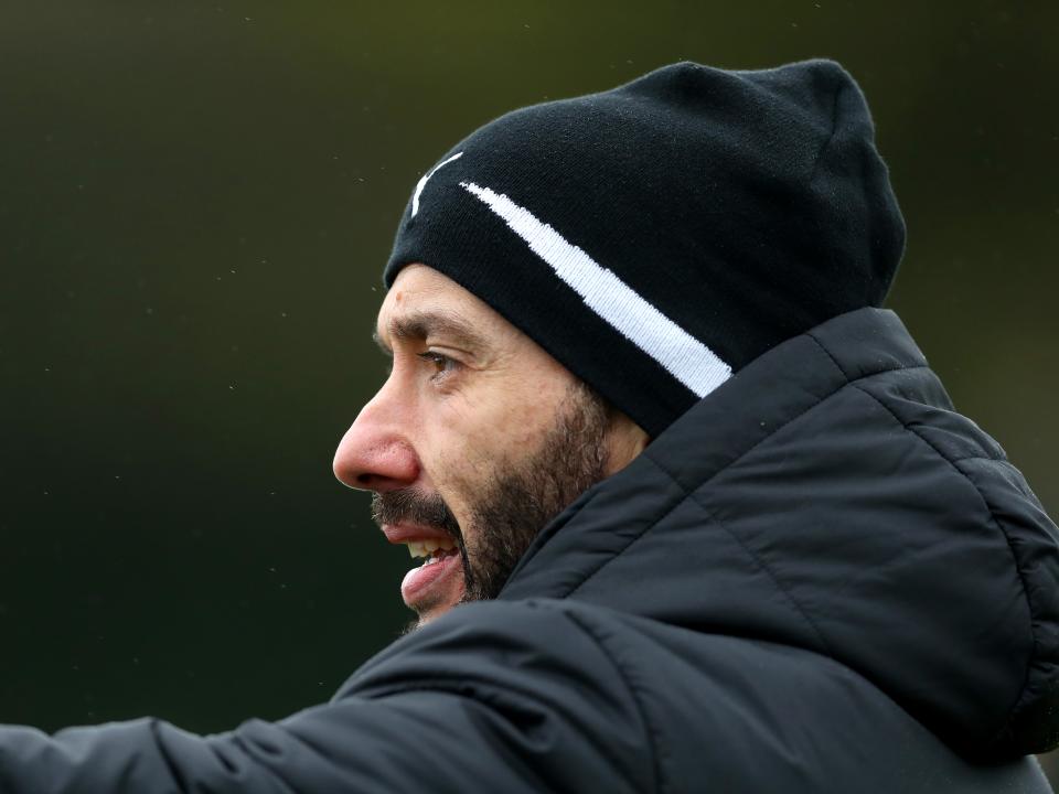 Carlos Corberán in a hat and a coat on the training pitch