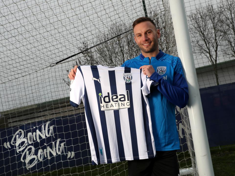 Andi Weimann smiling while holding up an Albion shirt