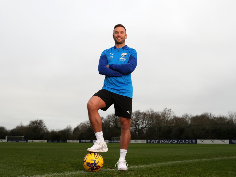 Andi Weimann smiling at the camera stood up with his foot on a ball and his arms folded