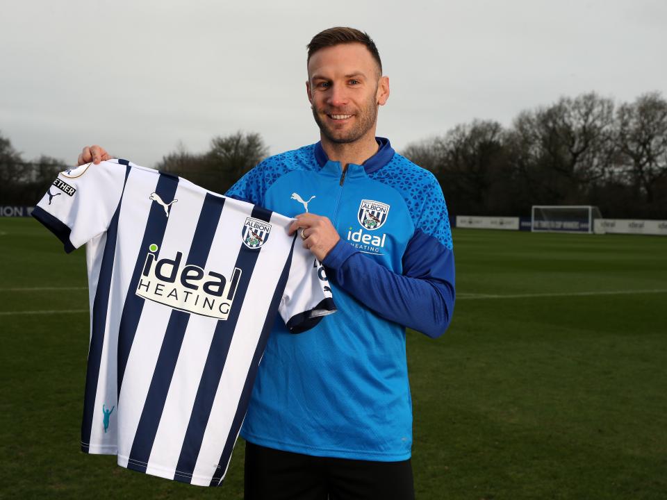 Andi Weimann smiling at the camera while holding up a home shirt