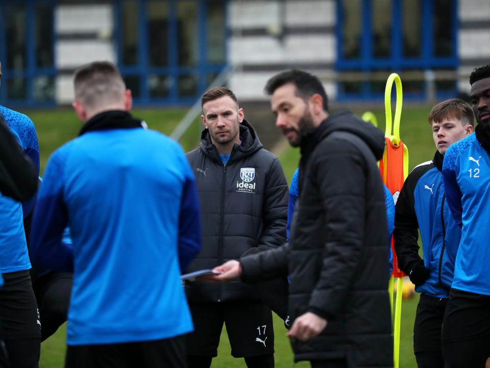 Andi Weimann watching Carlos Corberán deliver a speech during a training session
