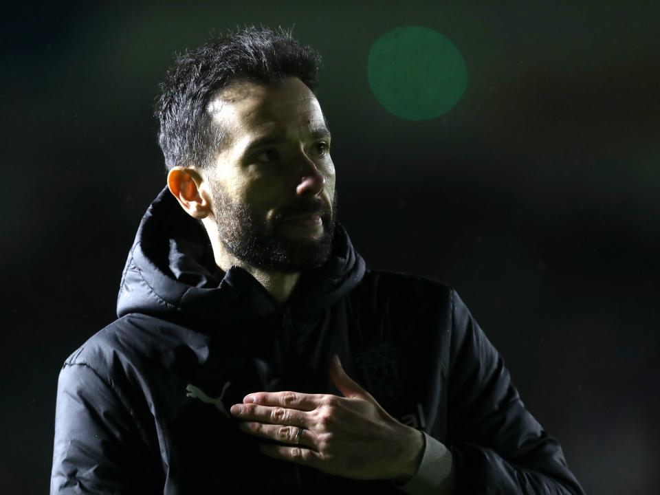 Carlos Corberan touches his heart as he looks at Albion fans in the away end at Plymouth