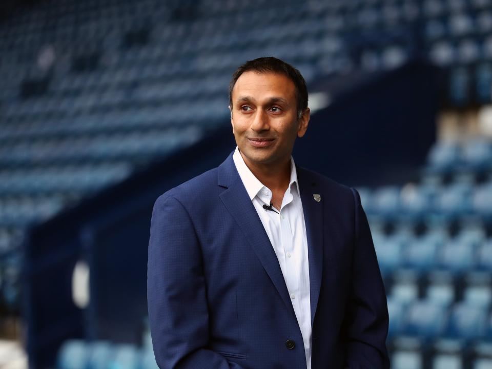 Shilen Patel looking out on to the pitch while walking along the blue track in front of the West Stand at The Hawthorns