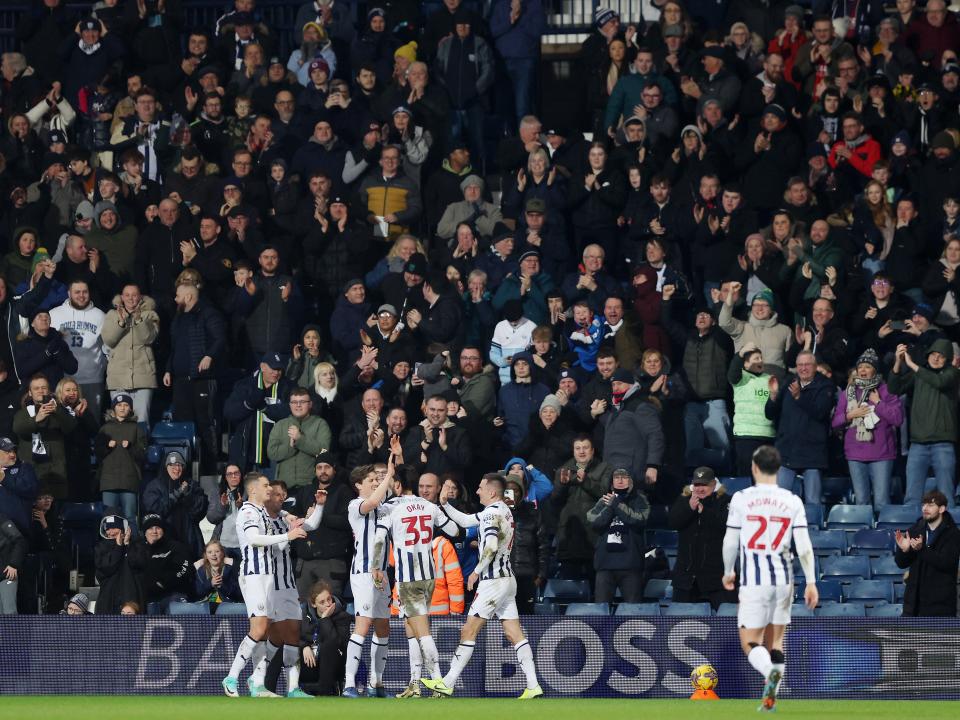 Albion players celebrate scoring against Cardiff with supporters in the stands behind them