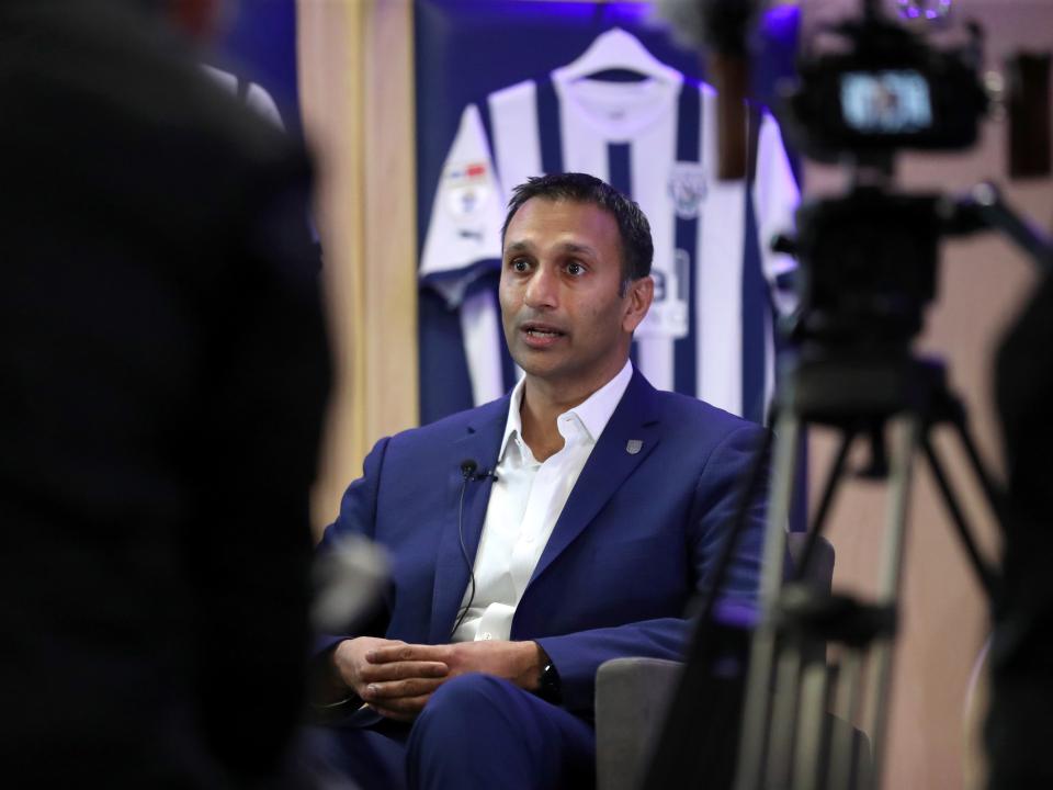 Shilen Patel is interviewed by WBA TV in the home dressing room at The Hawthorns with an Albion shirt behind him and the club cameras to the right of the photo