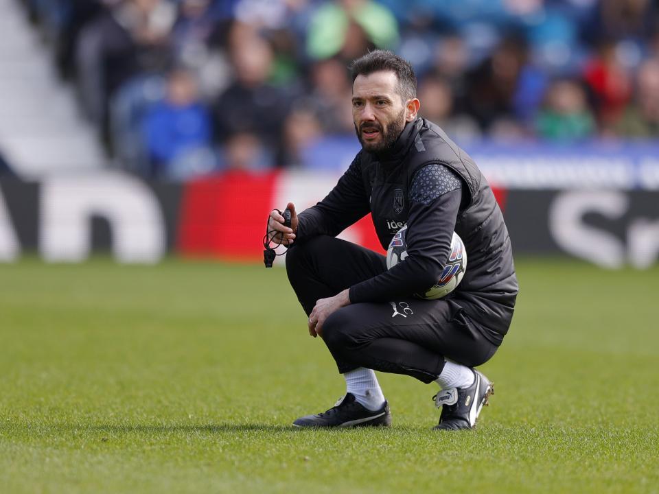 Carlos Corberán crouched down watching a training session at The Hawthorns