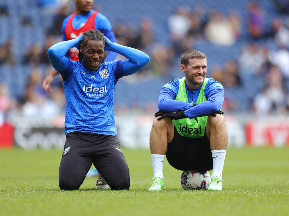 Brandon Thomas-Asante with his hands on his head smiling with John Swift sat on a ball next to him smiling at The Hawthorns