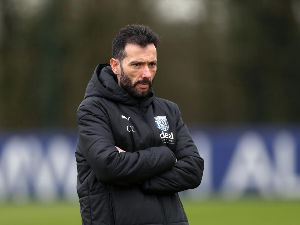 Carlos Corberán wearing a black coat while watching a training session with his arms crossed