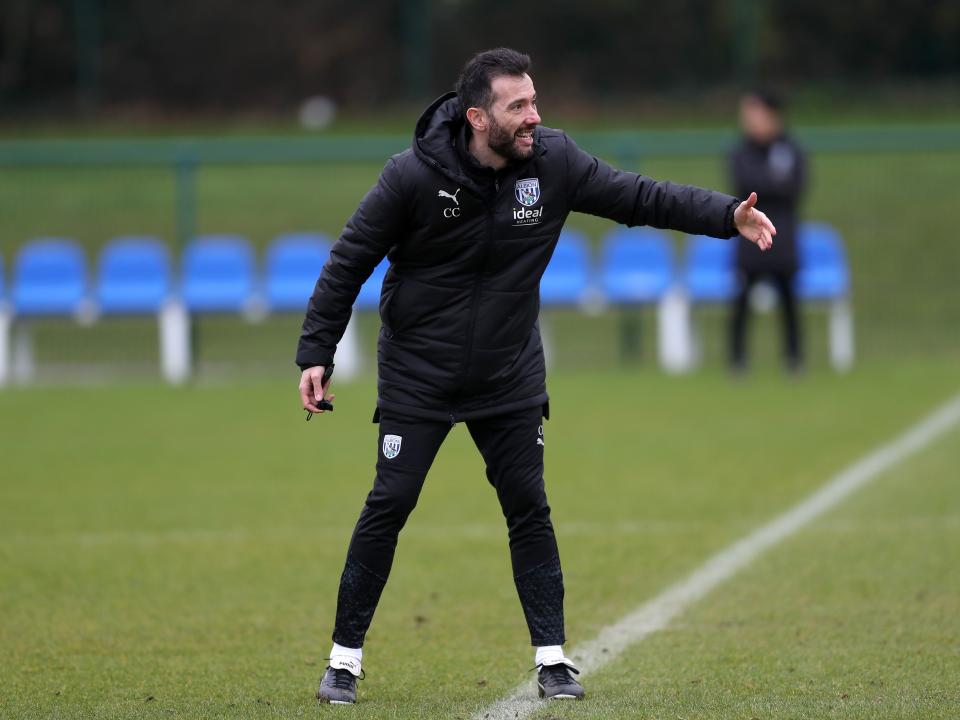 Carlos Corberán wearing a black coat while delivering instructions 