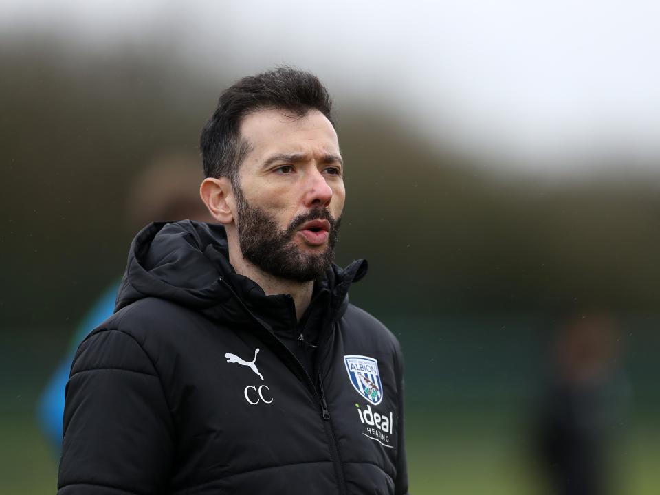 Carlos Corberán wearing a black coat while watching a training session