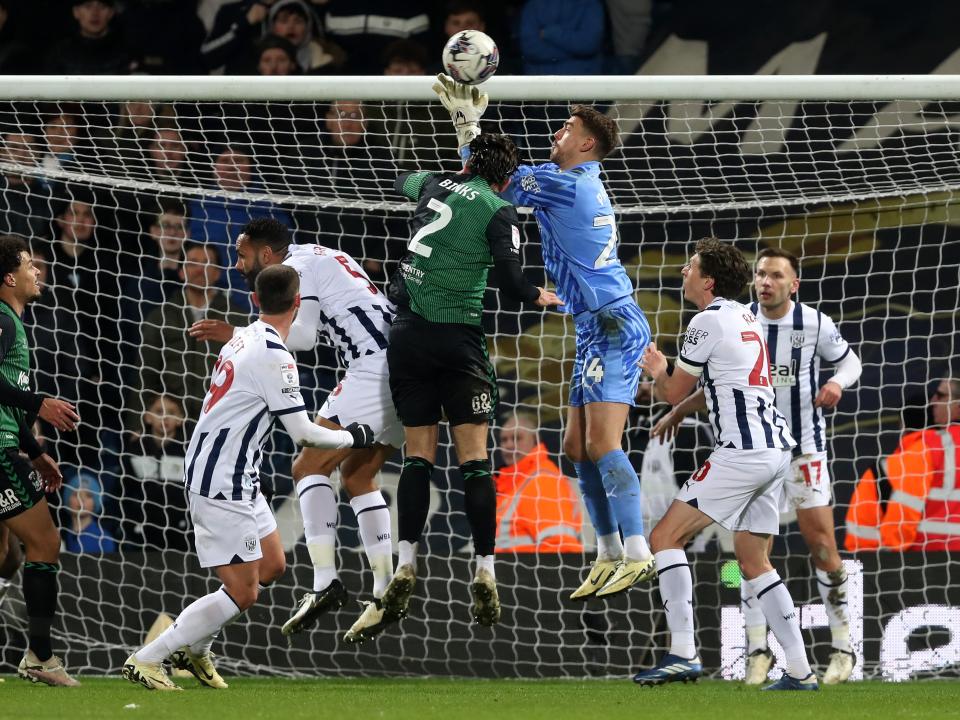 Alex Palmer jumping for the ball in the air under pressure by a Coventry player 