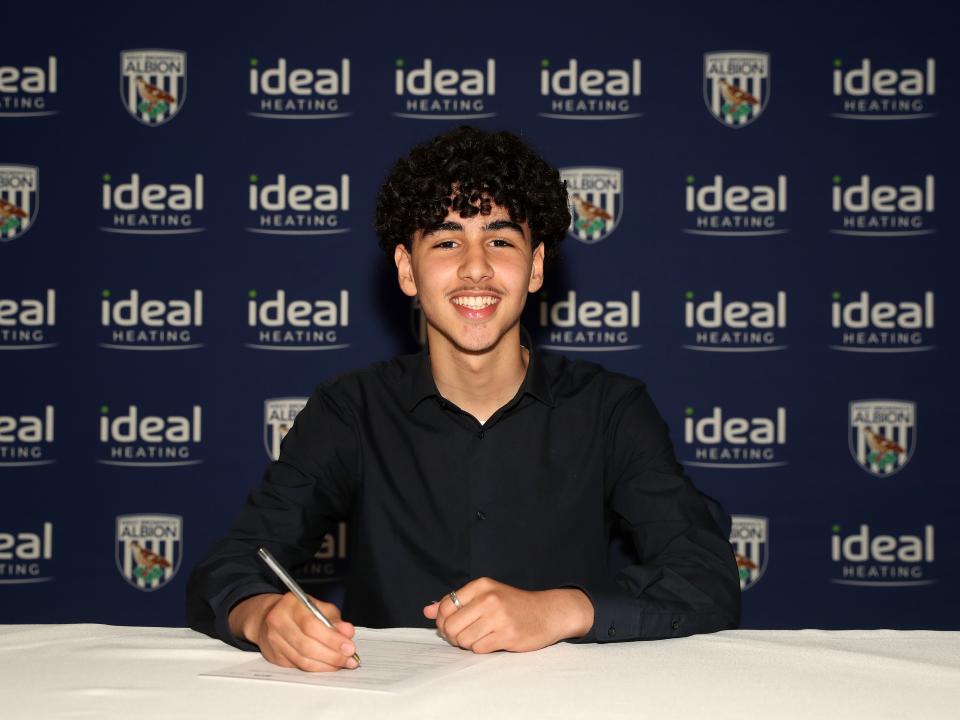 A photo of Adam Letlat signing his scholarship deal