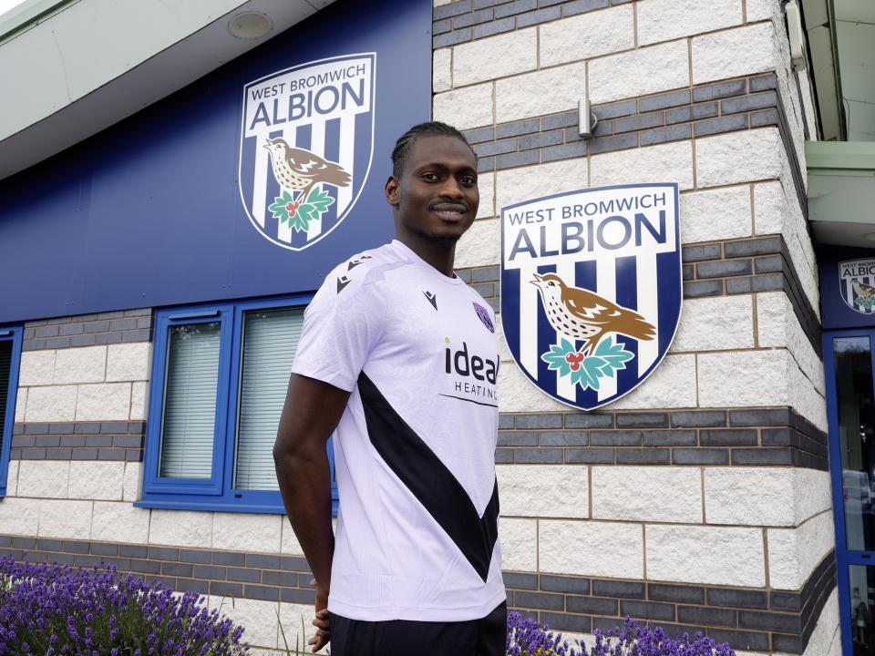 Ousmane Diakité smiling at the camera while stood outside the training ground entrance 
