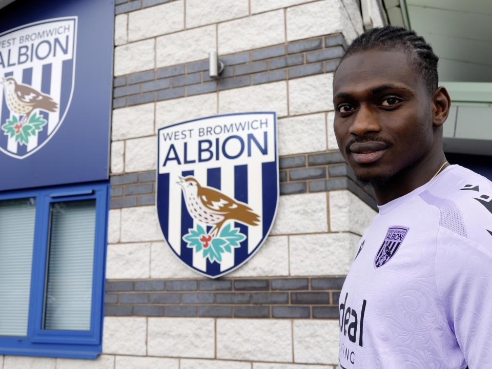 Ousmane Diakité smiling at the camera while stood outside the training ground entrance 