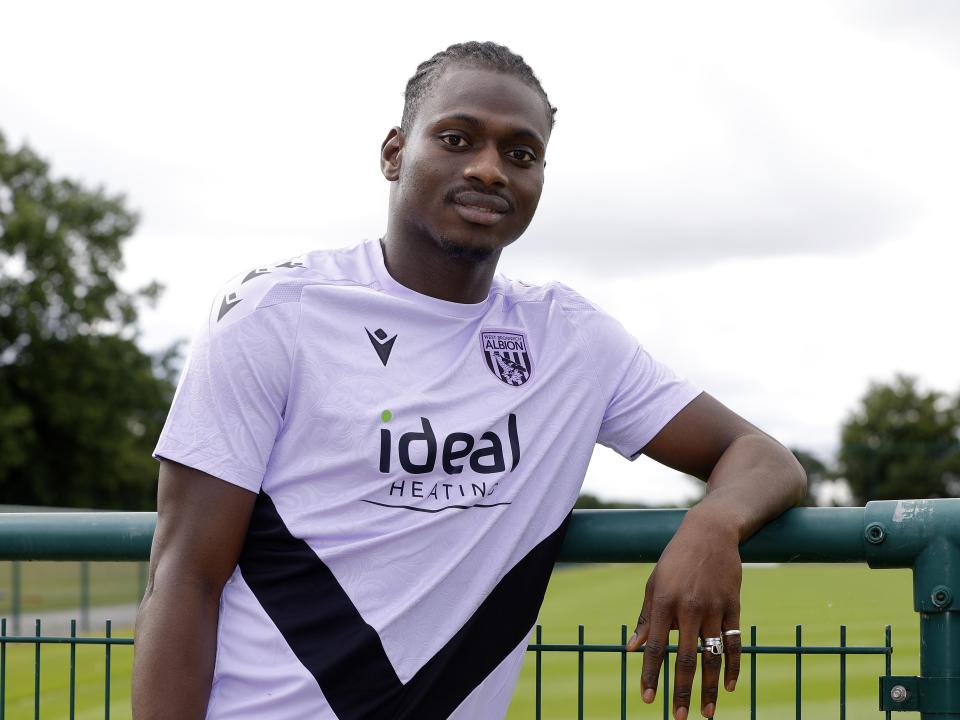Ousmane Diakité smiling at the camera while leaning on a fence 