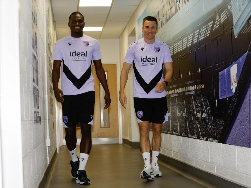 Ousmane Diakité and Jed Wallace chatting while walking down a corridor 