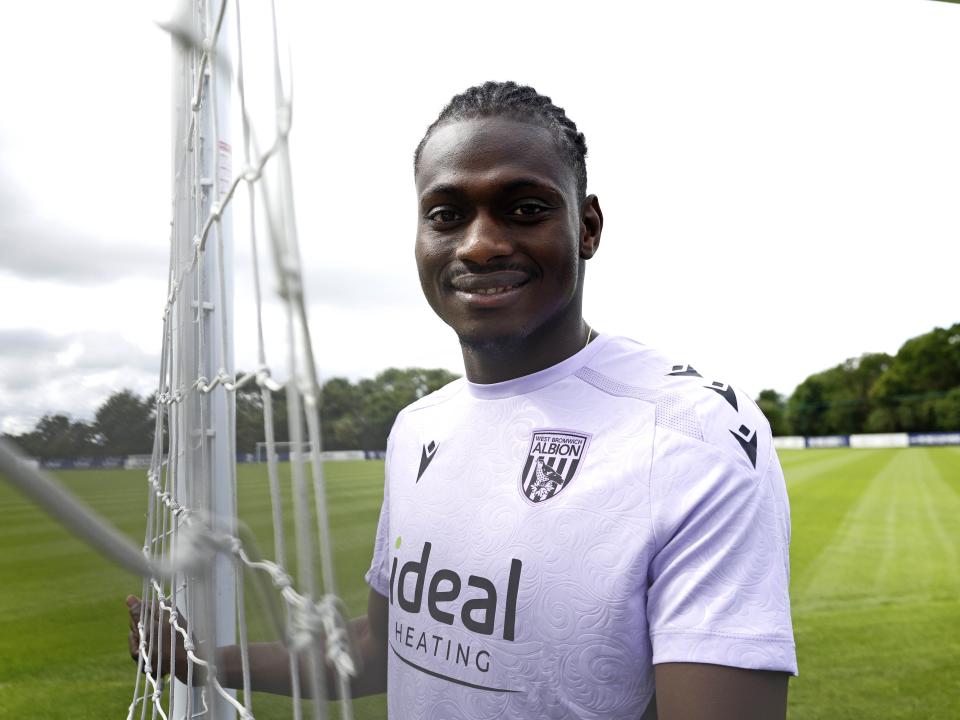 Ousmane Diakité smiling at the camera while stood outside 