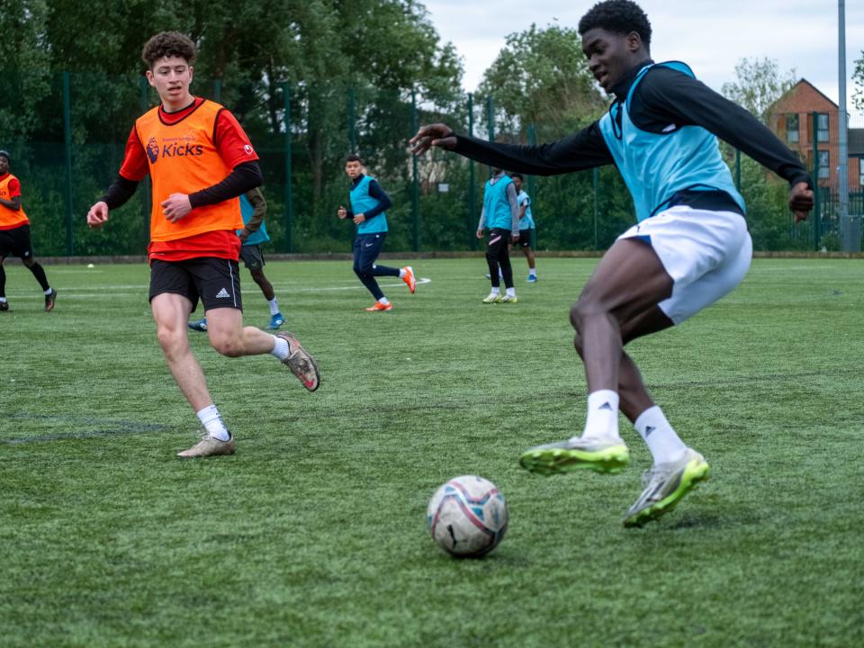 Player (Aqua blue)gaining control of the ball to make a cross, with defender (Orange) takes to cut him off.