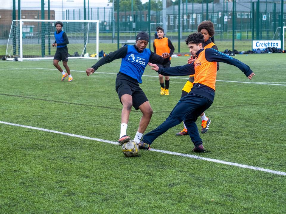 Two players (Dark blue & Orange) challenge for the ball.