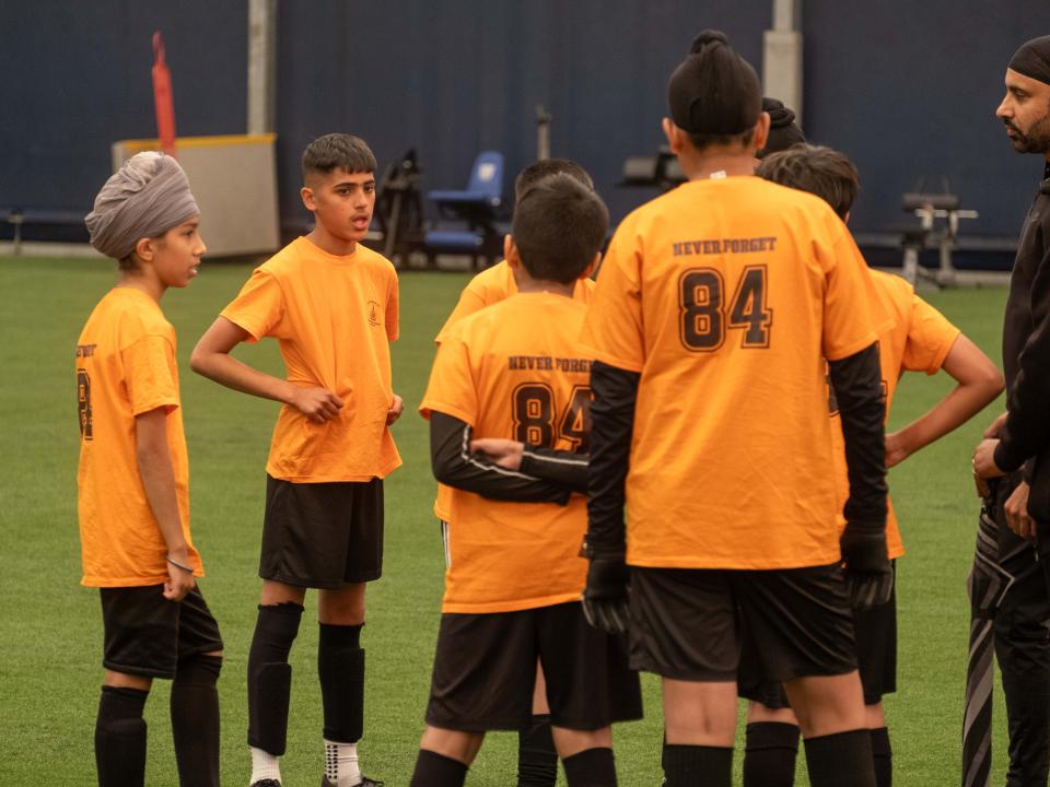 A team wearing orange gather in a huddle during our South Asian Emerging Talent Festival in the Academy Dome.