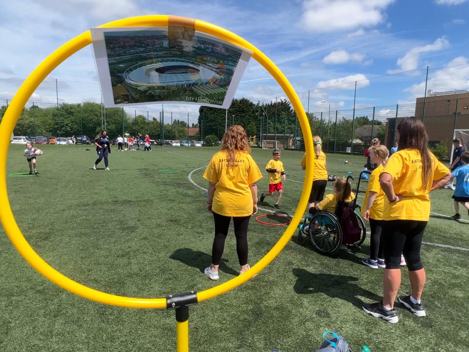 Student participating in activities with a hole on a stick in the forefront of the photo.