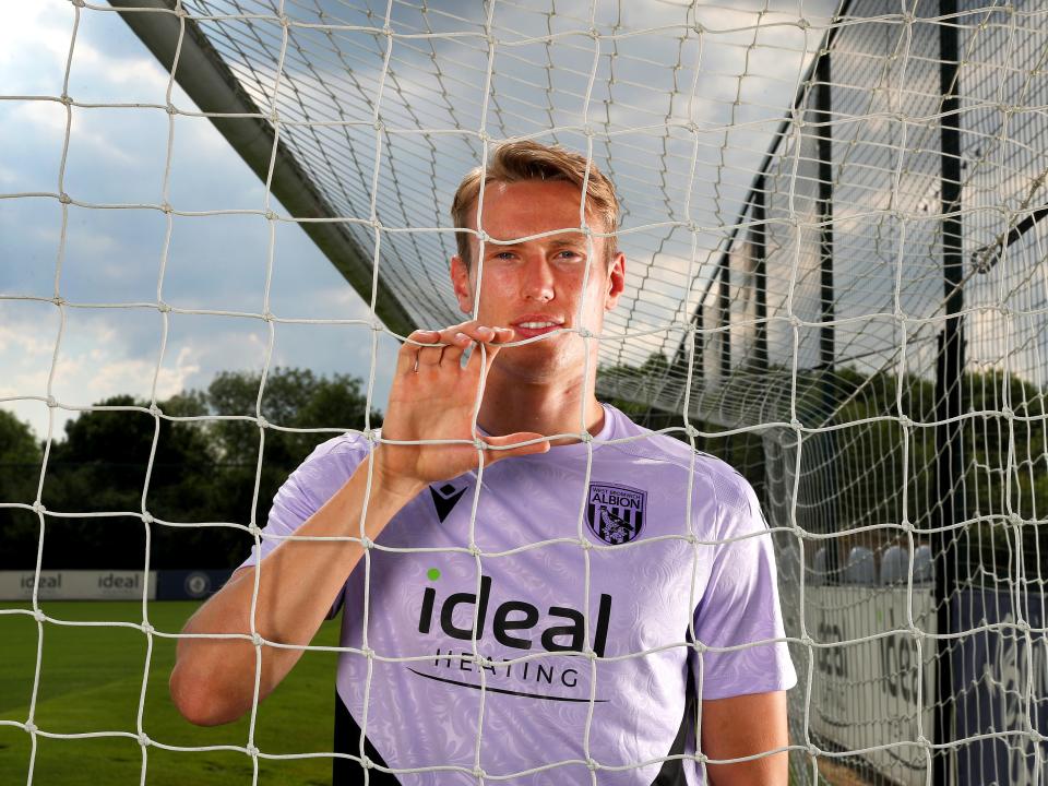 Torbjørn Heggem smiling at the camera while looking through a goal net
