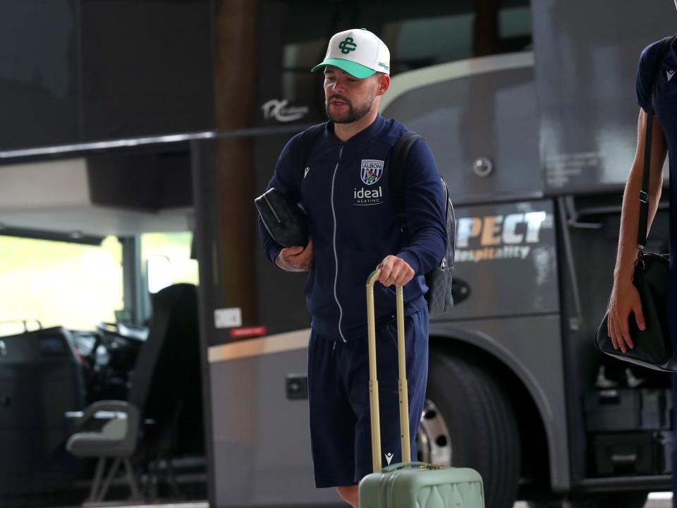 Alex Mowatt arriving at St. George's Park pushing a suitcase wearing a cap
