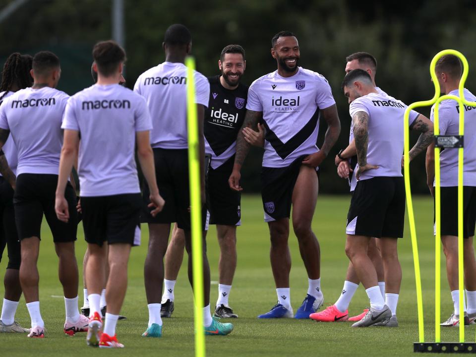 Several players smiling during a break in training with coach Damia Abella 
