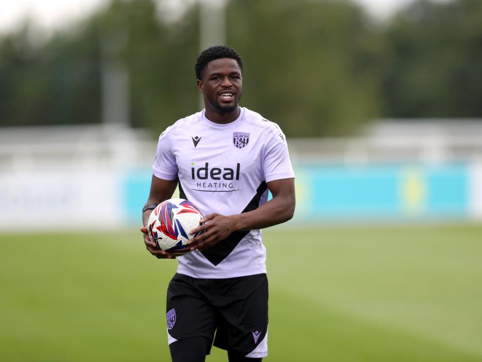 Josh Maja smiling and holding a ball on the training pitch at St. George's Park