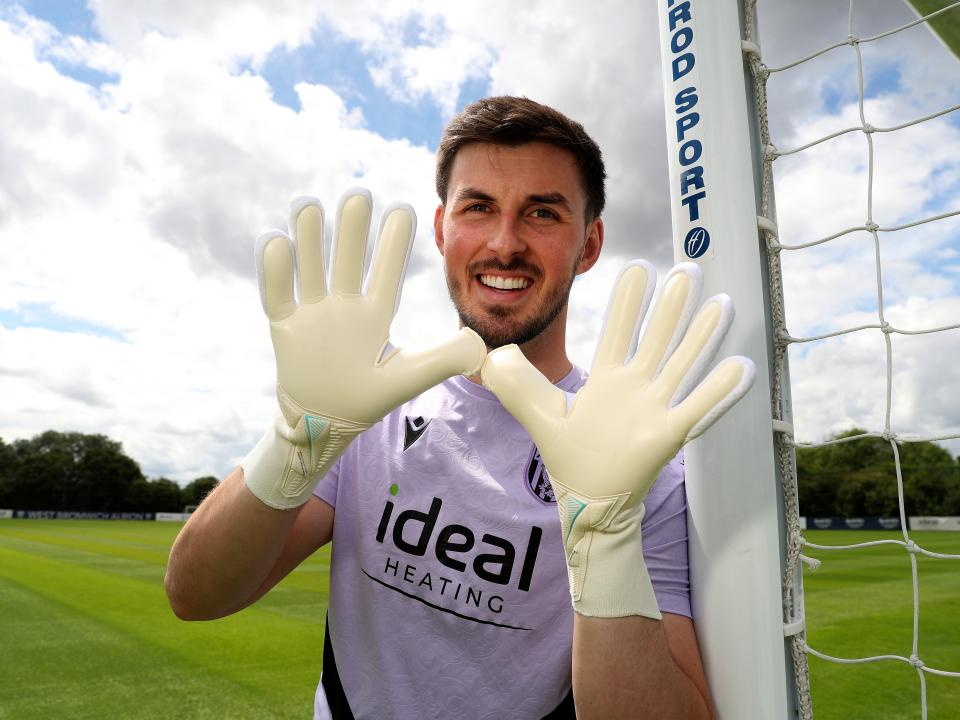 Joe Wildsmith smiling at the camera while holding his gloves up