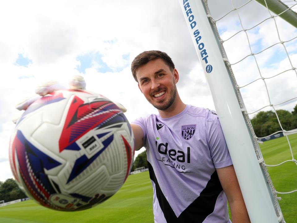 Joe Wildsmith smiling at the camera while holding a football