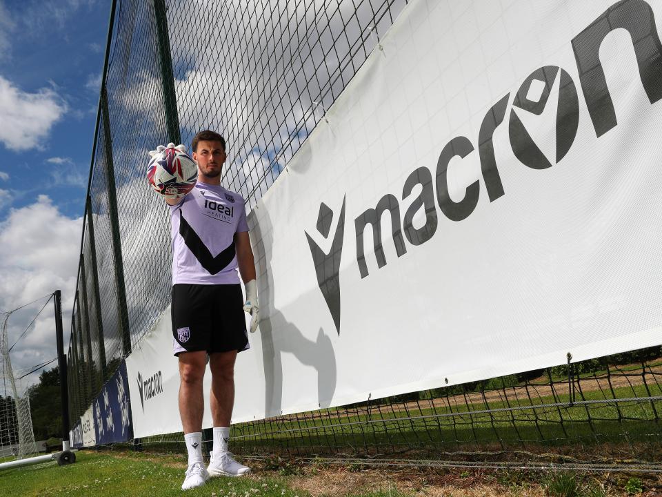 Joe Wildsmith smiling at the camera while holding a football