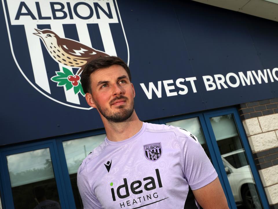Joe Wildsmith stood in front of Albion branding at the training ground 