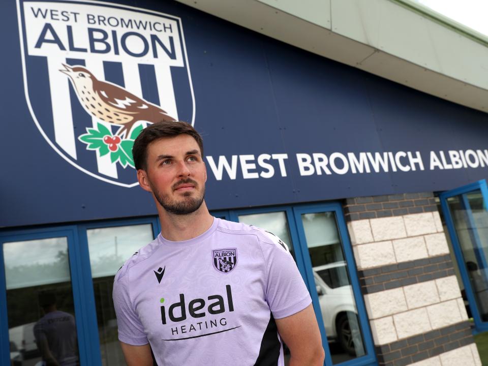 Joe Wildsmith stood in front of Albion branding at the training ground 