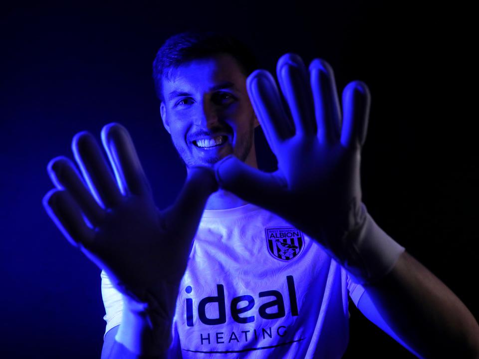 Joe Wildsmith holding his gloves up while looking at the camera smiling 
